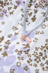 Short de baño blanco con estampado floral en tonos lila y marrón. Cuenta con cintura elástica ajustable con cordón, protección UV50, dos bolsillos laterales, un bolsillo trasero con cierre y suspensor de malla fina hipoalergénica.