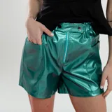 Short de cuero sintético color verde esmeralda, con cintura elástica y cierre frontal con cremallera.