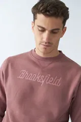 Buzo de felpa color rosa con logo estampado, cuello redondo, mangas largas y puños.