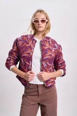 Campera bomber corta color bordó con estampado abstracto en tonos naranja y lila, cierre frontal y mangas largas abullonadas.