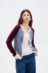 Cardigan de punto con diseño color block, presenta cuerpo en color celeste, mangas en color bordó y detalles de botones y bordes en color rosado. Posee cuello redondo y mangas largas.