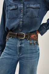 Cinturón faja de cuero marrón con diseño estilo boho, decorado con tachas metálicas, bordados geométricos en tonos naranjas y rojizos, y dijes colgantes tipo monedas en el borde inferior.