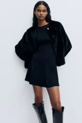 Vestido corto sin mangas en punto roma, de color negro, con cuerpo entallado, escote redondo y falda con vuelo.