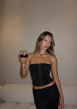 Corset negro strapless con diseño fruncido en el cuerpo y cierre frontal con corchetes.