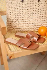 Sandalias planas de cuero sintético con estampa de cocodrilo, color marrón, con diseño de tira ancha en forma de 'H' en el empeine y punta cuadrada.