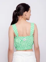 Top blanco con estampado floral en tonos naranja y lila, de corte cropped y breteles anchos.