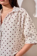 Blusa de lino y viscosa color blanco con estampado de lunares marrones, de manga corta y cuello camisero con cierre frontal de botones.