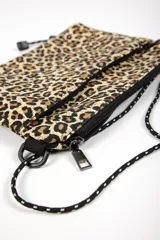Cartera tipo bandolera con estampado animal print de leopardo, cierre de cremallera y correa ajustable de cordón negro.