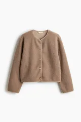 Chaqueta de sherpa suave con cuello redondo, corte holgado y cierre frontal con botones metálicos. Presenta ribetes de cinta en los bordes.