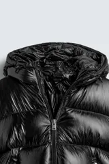 Campera puffer negra con capucha, cierre frontal con cremallera, bolsillos laterales con cremallera y puños elásticos.
