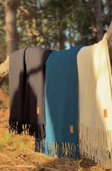 Bufanda de lana merino de tejido doble, con diseño liso y flecos en los extremos. Incluye una pequeña etiqueta de cuero sintético con logo grabado.