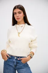 Sweater de punto con diseño de trenzas, color crudo, de cuello redondo y manga larga con puños acanalados.