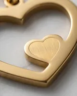 Dije de acero con baño de oro en forma de corazón calado con un pequeño corazón sólido en su interior.