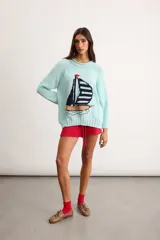Sweater de punto de algodón color celeste, con diseño estampado de un velero en el frente y cuello redondo.