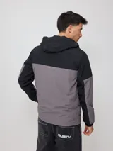 Campera rompevientos Rusty con diseño de bloques de color en azul marino y naranja. Presenta capucha, cierre frontal completo y puños elásticos.