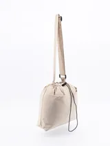 Bolso tipo tote de color beige, con diseño minimalista, cierre superior mediante cordón ajustable y costuras visibles en contraste.