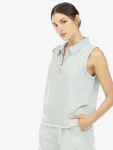 Musculosa de denim celeste, con cuello polo, escote en V con botones, de fit amplio y terminación desflecada en el bajo.