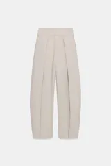 Pantalón balloon de tiro alto color beige con sutiles rayas, pliegues delanteros y bolsillos laterales.