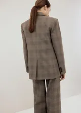 Blazer de corte sastrero con diseño a cuadros, confeccionado en una mezcla de lana, poliéster, viscosa y elastano. Presenta solapas clásicas, cierre frontal con un botón y bolsillos laterales con solapa.