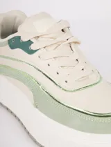 Zapatilla de plataforma con diseño de recortes en tonos blanco, beige y detalles metalizados plateados. Cuenta con suela texturizada y cierre mediante cordones.