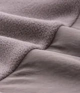 Buzo de fleece con cierre frontal completo y cuello alto. Presenta un diseño con recortes en tonos blanco y negro en las mangas y laterales, y cuenta con una estampa pequeña en el pecho.