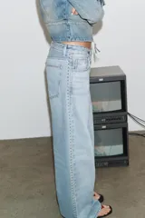 Jeans de tiro alto con diseño de pierna ancha y corte extra largo. Presenta cinco bolsillos clásicos y detalle de tachas metálicas a lo largo de las costuras laterales. Cierre frontal con cremallera y botón metálico.