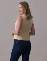 Chaleco sastrero negro con cuello solapado, escote en V, bolsillos simulados y cierre frontal cruzado con botones.