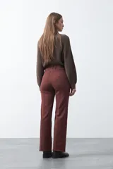 Pantalón de fit recto color beige, confeccionado en cotton spandex. Presenta costuras visibles y bordados decorativos en tono dorado/marrón claro. El ruedo del pantalón tiene un borde festoneado.