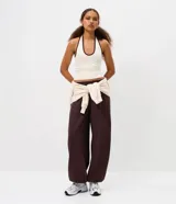 Pantalón estilo aladín de corte amplio y holgado, color marrón oscuro. Confeccionado en tejido de moletón con felpa interna, cuenta con cintura elástica y puños elásticos en los tobillos.