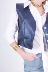 Brazalete dorado rígido con diseño geométrico de cuadrados calados.