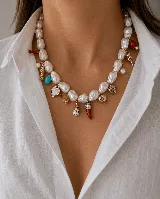 Collar corto compuesto por perlas barrocas irregulares, adornado con múltiples dijes colgantes que incluyen figuras de peces, corazones, elementos con piedras turquesas, una concha pequeña y un dije en forma de cuerno rojo.