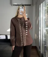 Camisa de manga larga color blanco con bordados geométricos en negro a lo largo de la botonadura frontal y en los puños. Presenta cuello mao y cierre frontal con botones.