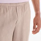 Bermuda beige de felpa ligera, de corte recto y holgado, con cintura elástica.