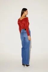 Blusa negra con escote off-shoulder y mangas largas ajustadas.