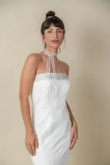 Vestido largo blanco de crepé, corte sirena, palabra de honor con bordado de piedras en el escote y cola pequeña.