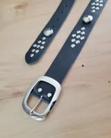 Cinto de cuero negro con hebilla metálica plateada y tachas redondas plateadas a lo largo de la tira.