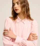 Camisa celeste de crepé con cuello inglés, manga larga abullonada y abotonadura frontal.