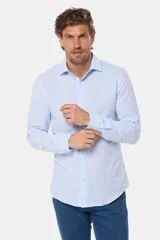 Camisa de manga larga, corte slim fit, color celeste con finas rayas verticales blancas. Presenta cuello camisero y un pequeño logo bordado en el pecho.