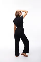 Mono negro con cuello camisero, mangas cortas, cinturón con hebilla circular de bambú y bolsillos laterales.