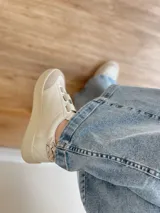 Zapatillas blancas de cuero con detalles en cuero gamuzado color beige en la puntera y ajuste con velcro. Presenta detalle de cuero con estampado reptil en el talón.