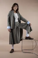 Falda midi gris con diseño de espiga, corte evasé y abertura frontal.