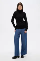 Polera de lyocell color negro, con cuello alto y ajuste al cuerpo, de manga larga.