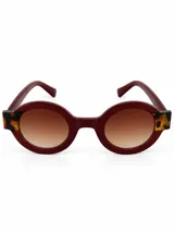 Lentes de sol circulares con armazón bordó y detalles animal print en las esquinas, con cristales degradé en tonos marrones.