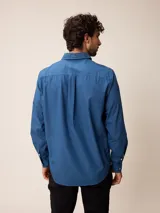 Camisa de manga larga en color azul, confeccionada en algodón con técnica de teñido garment dye. Presenta cuello abotonado, cierre frontal con botones y un bolsillo en el pecho con detalle bordado.