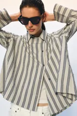 Camisa de corte oversize confeccionada en mezcla de viscosa, con estampado de rayas verticales. Presenta cuello solapa, cierre frontal con botones y mangas largas con puños amplios.