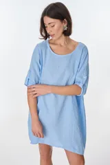 Vestido corto color beige de lino, con cuello redondo, corte oversize y mangas 3/4 con botón. Presenta bolsillos laterales.