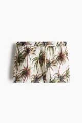 Short de baño con estampado de palmeras, cintura elástica con cordón ajustable, bolsillos laterales y bolsillo trasero. Cuenta con suspensor interior de malla y aberturas laterales en el ruedo.