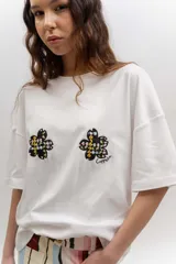 Remera de algodón blanca, de corte oversize, con mangas cortas y dos aplicaciones de flores bordadas en el frente.
