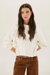 Buzo negro de corte cropped con mangas largas abullonadas y costuras a la vista en color blanco.