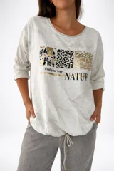 Remera de la línea italiana, color blanco con estampado frontal de animal print en tonos dorados y negros, y la frase "Find your true NATURE". Tiene cuello redondo, mangas largas y cordón regulable en la parte inferior para ajustar el largo.